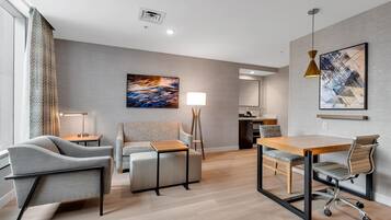 Una habitación de hotel moderna con sofá, escritorio, silla, lámpara y obras de arte en las paredes.