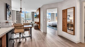 Una habitación de hotel moderna con zona de comedor, una cama grande y vistas a la ciudad.