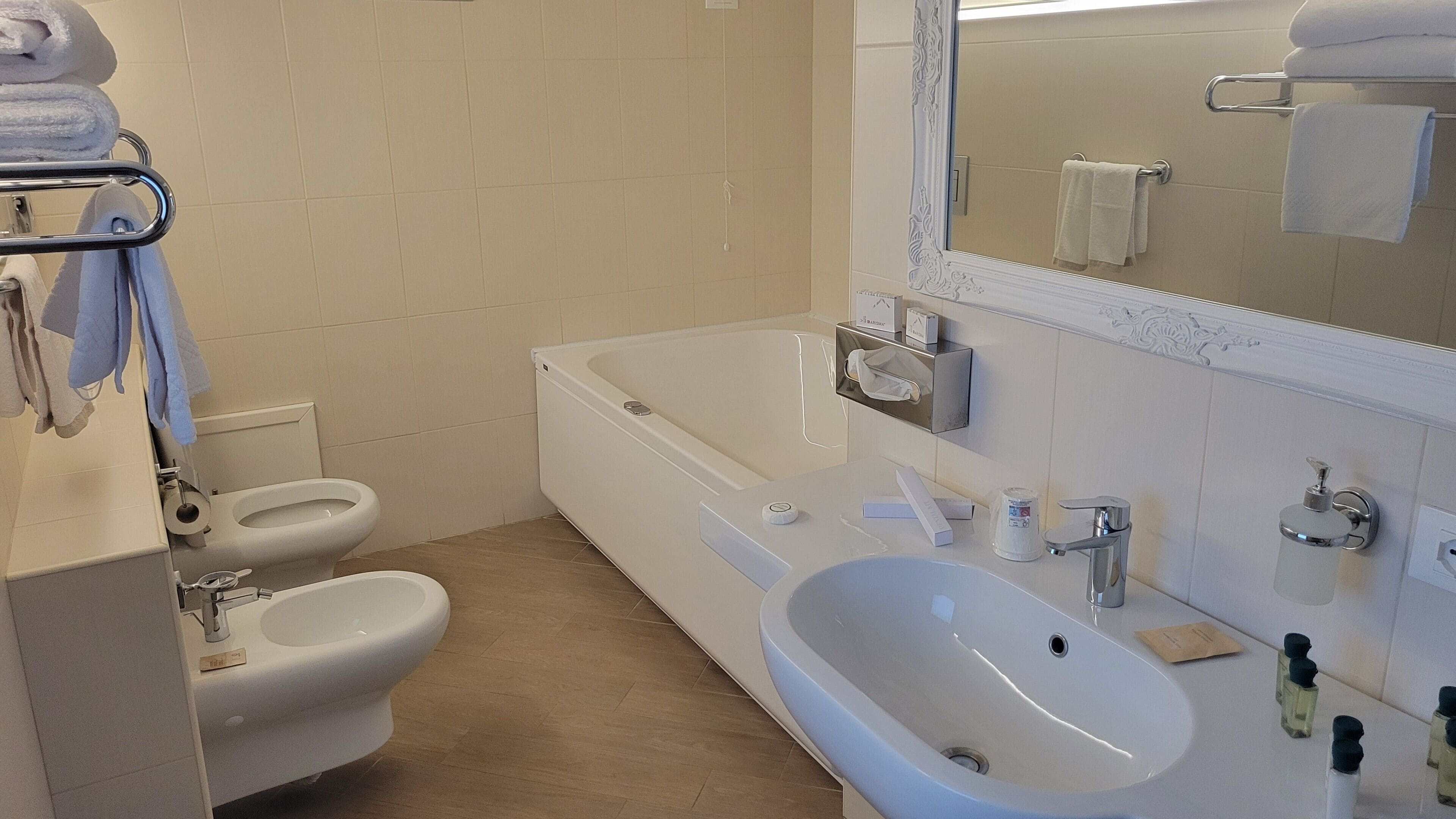 Ein Badezimmer mit Toilette, Bidet, Badewanne, Waschbecken und einem Spiegel.