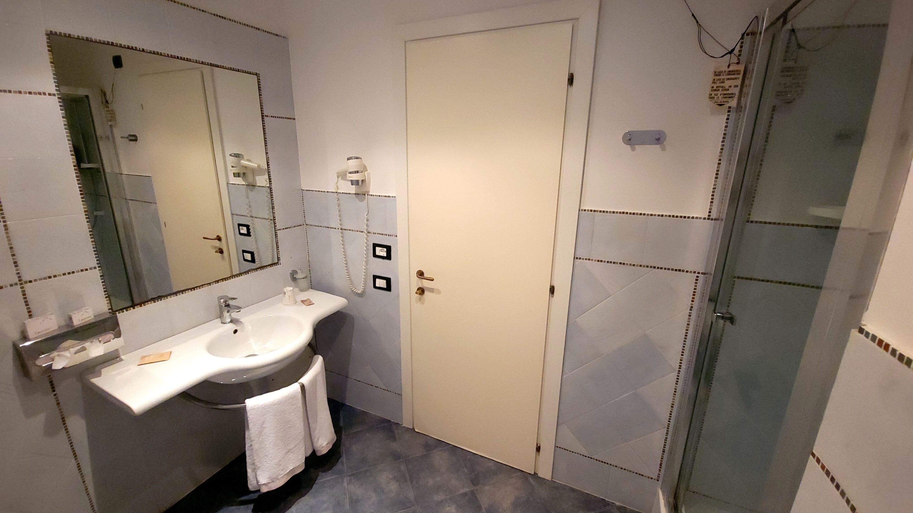 Un bagno con lavandino, specchio e doccia.