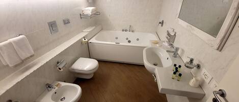 Ein modernes Badezimmer mit einer Badewanne, einem Waschbecken, einem Bidet und einer Toilette.