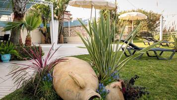 Un giardino con grandi vasi ornamentali, una piscina e poltrone da relax.