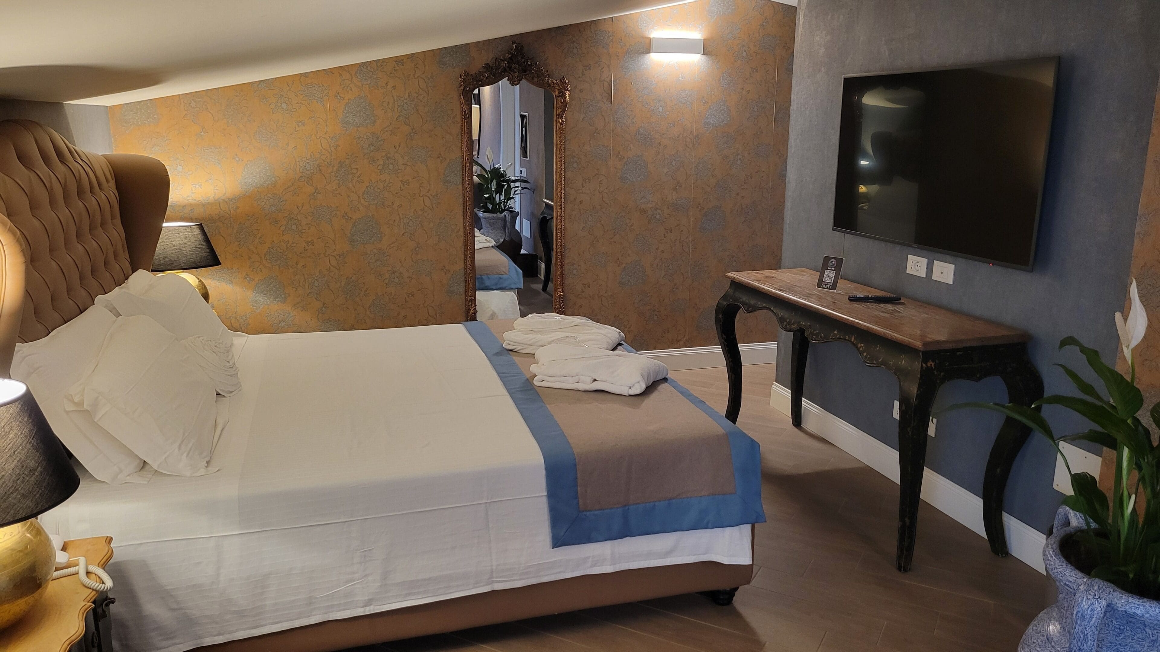 Ett hotellrum med en säng, ett skrivbord, en tv och en spegel.