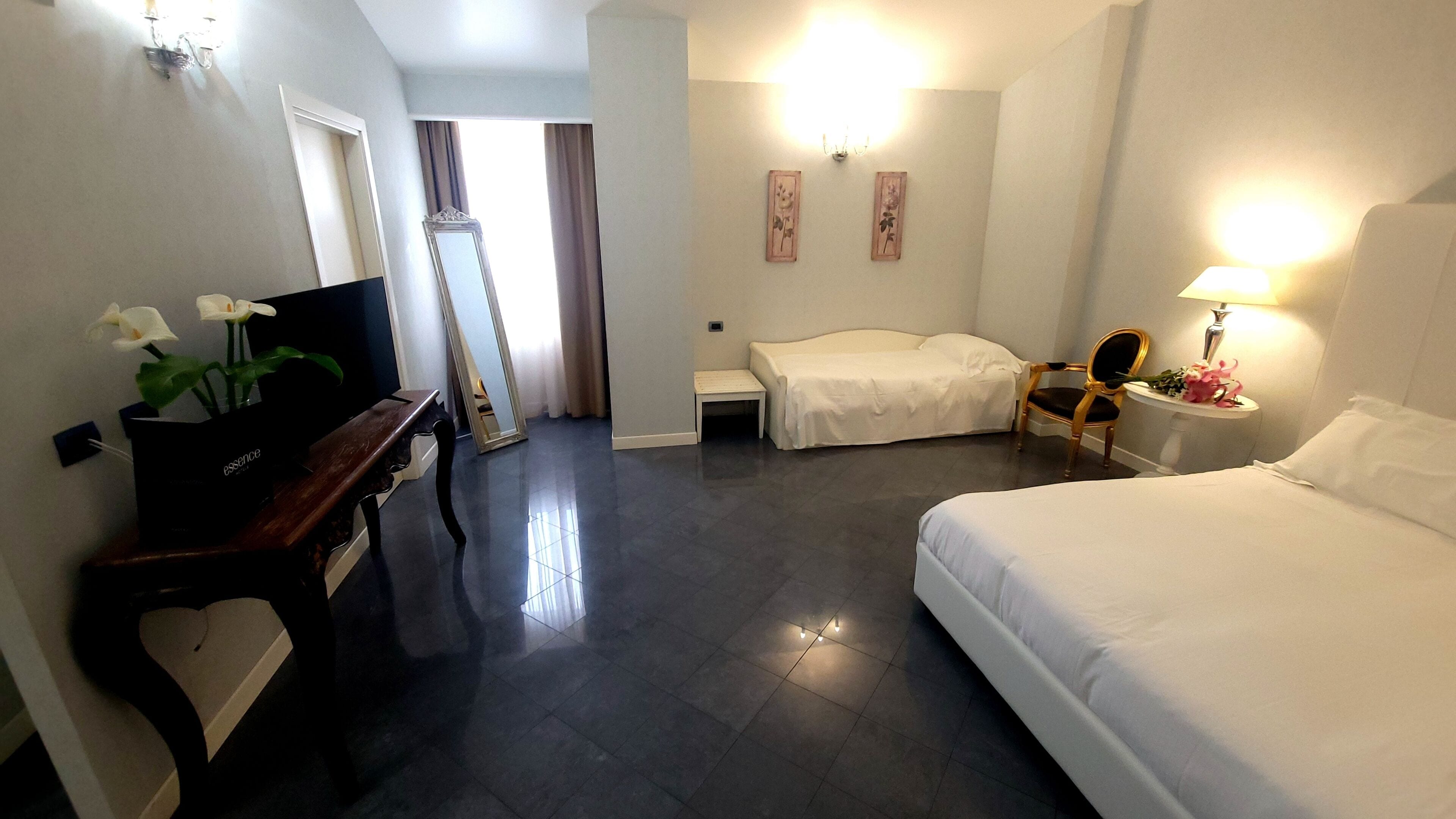 A hotel room with a bed, a desk, a chair, and a television.