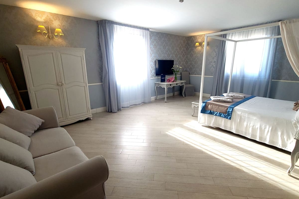Ein Schlafzimmer mit Bett, Sofa, Fernseher, Kleiderschrank und Nachttisch.
