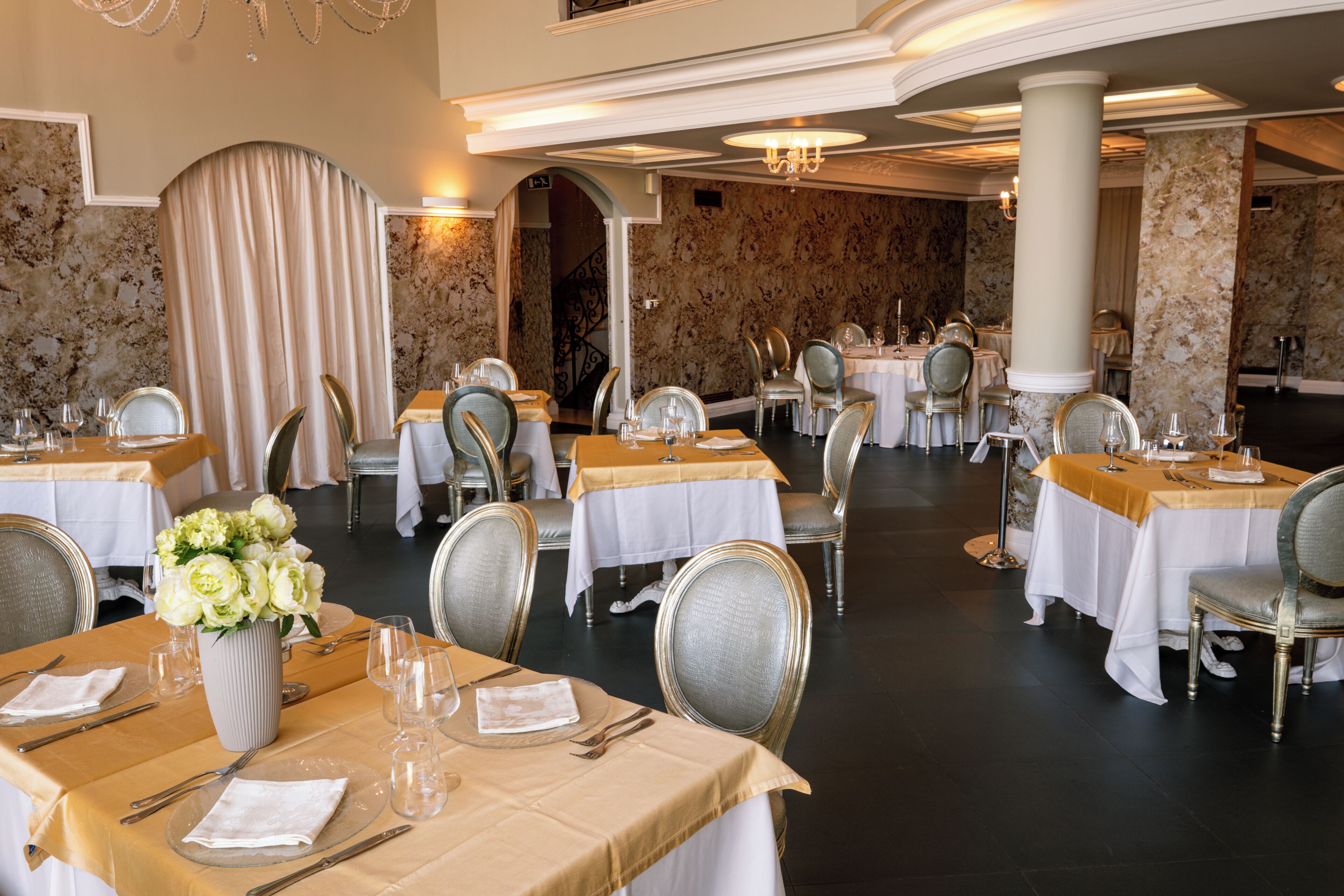 Una sala da pranzo formale con diversi tavoli, sedie e un lampadario.