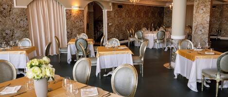 Una sala da pranzo formale con diversi tavoli, sedie e un lampadario.