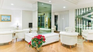 A modern living room with white furniture, a glass coffee table, and a potted plant. - Hotel City (Montesilvano)