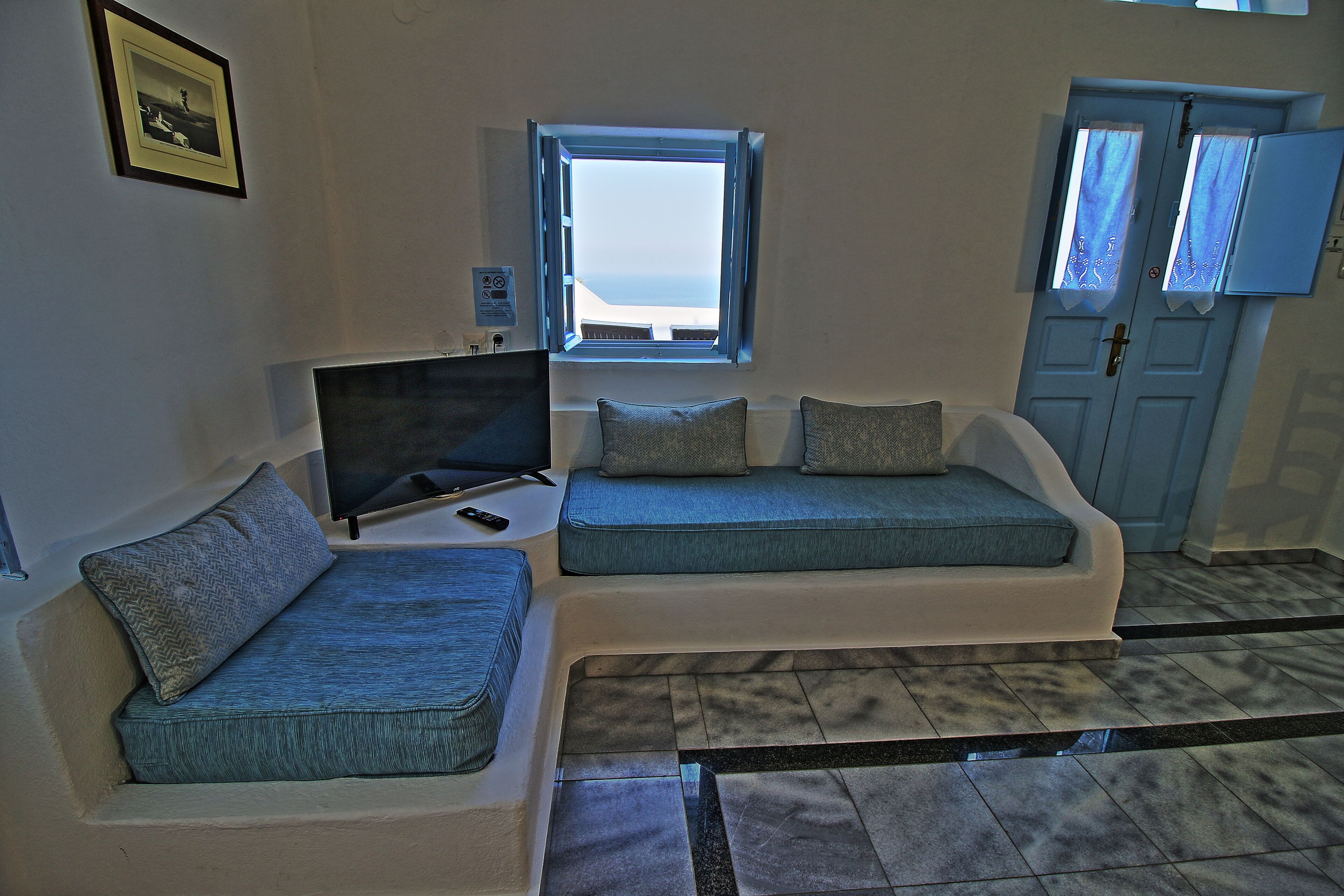 A room with a sofa, a television, a window, and a door.