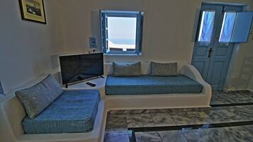 A room with a sofa, a television, a window, and a door.