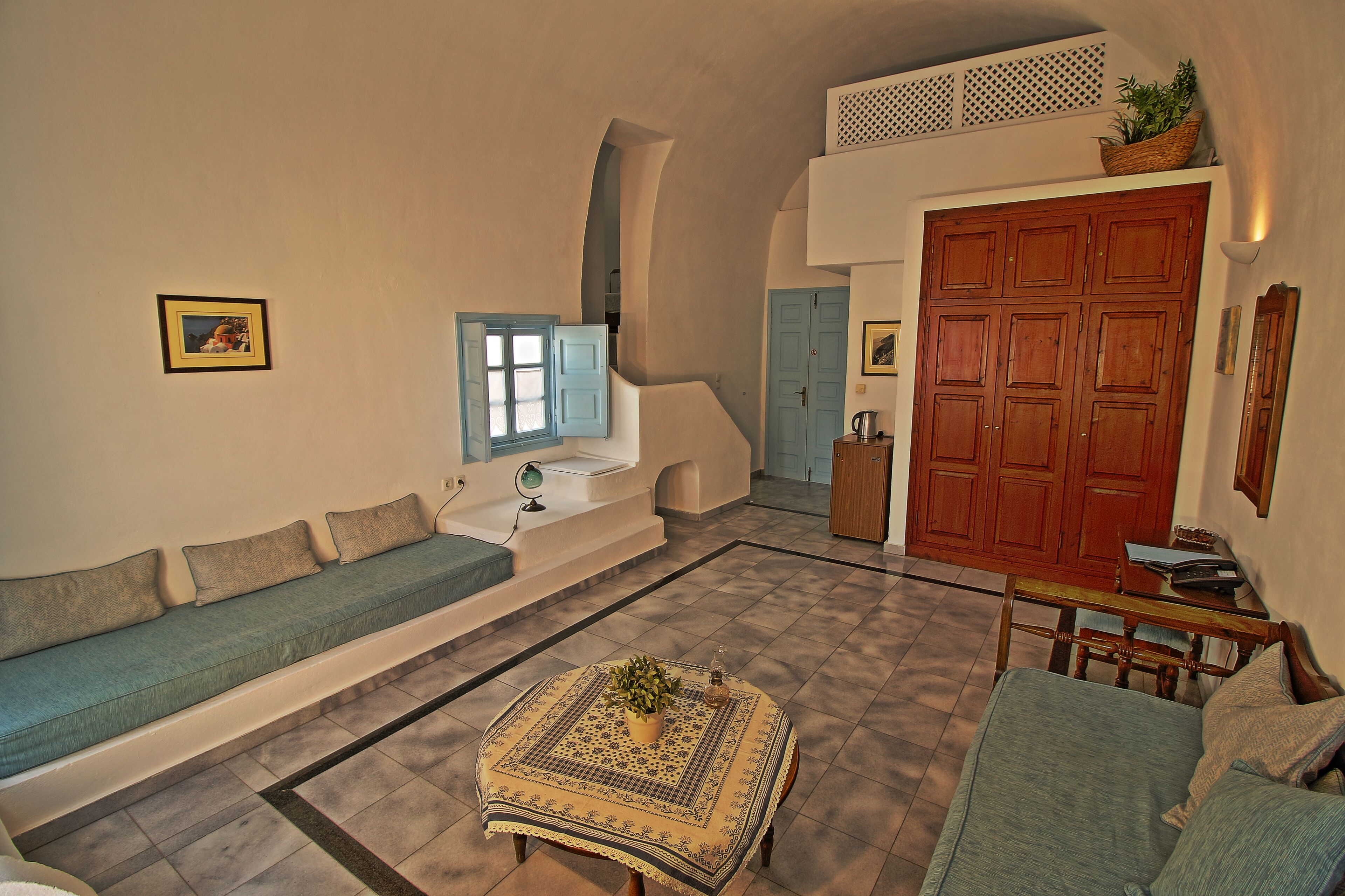 A spacious living area with a sofa, a coffee table, and a dining table. There is a staircase leading to an upper level.