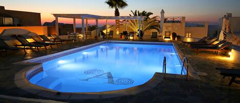 Een buitenzwembad, parasols bij het zwembad en ligstoelen