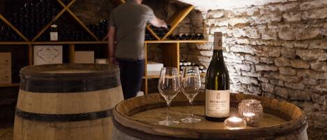 Une cave à vin avec des barriques en bois et des étagères remplies de bouteilles de vin.