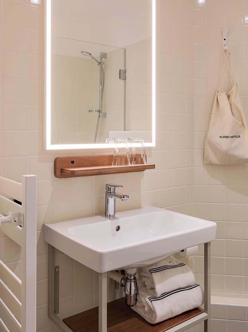 A bathroom with a white sink, a mirror, a towel rack, and a shower.