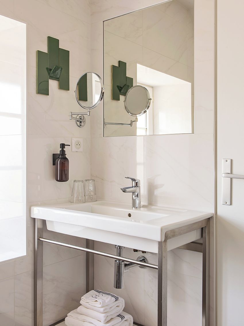 Un bagno moderno con un lavandino bianco, due specchi e un porta asciugamani.
