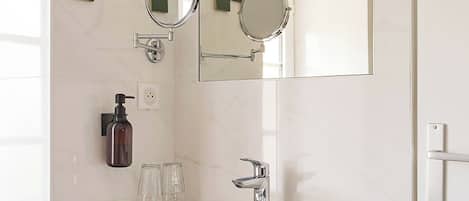 A modern bathroom with a white sink, two mirrors, and a towel rack.
