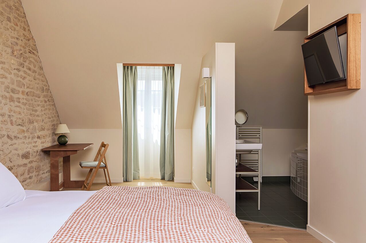 A bedroom with a bed, a desk, a chair, a TV, and a wardrobe.
