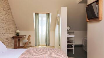 A bedroom with a bed, a desk, a chair, a TV, and a wardrobe.