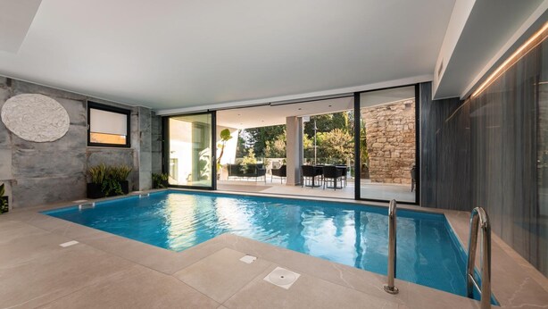 An indoor swimming pool with clear glass walls, a stone wall, and a modern interior design. - Hotel Cittar (Novigrad)