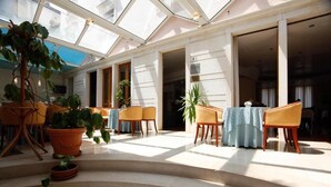 A hotel lobby with a glass ceiling, seating area, and potted plants. - Hotel Cittar (Novigrad)