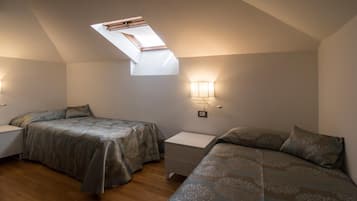Une chambre avec deux lits, une lucarne et des lampes de chevet.