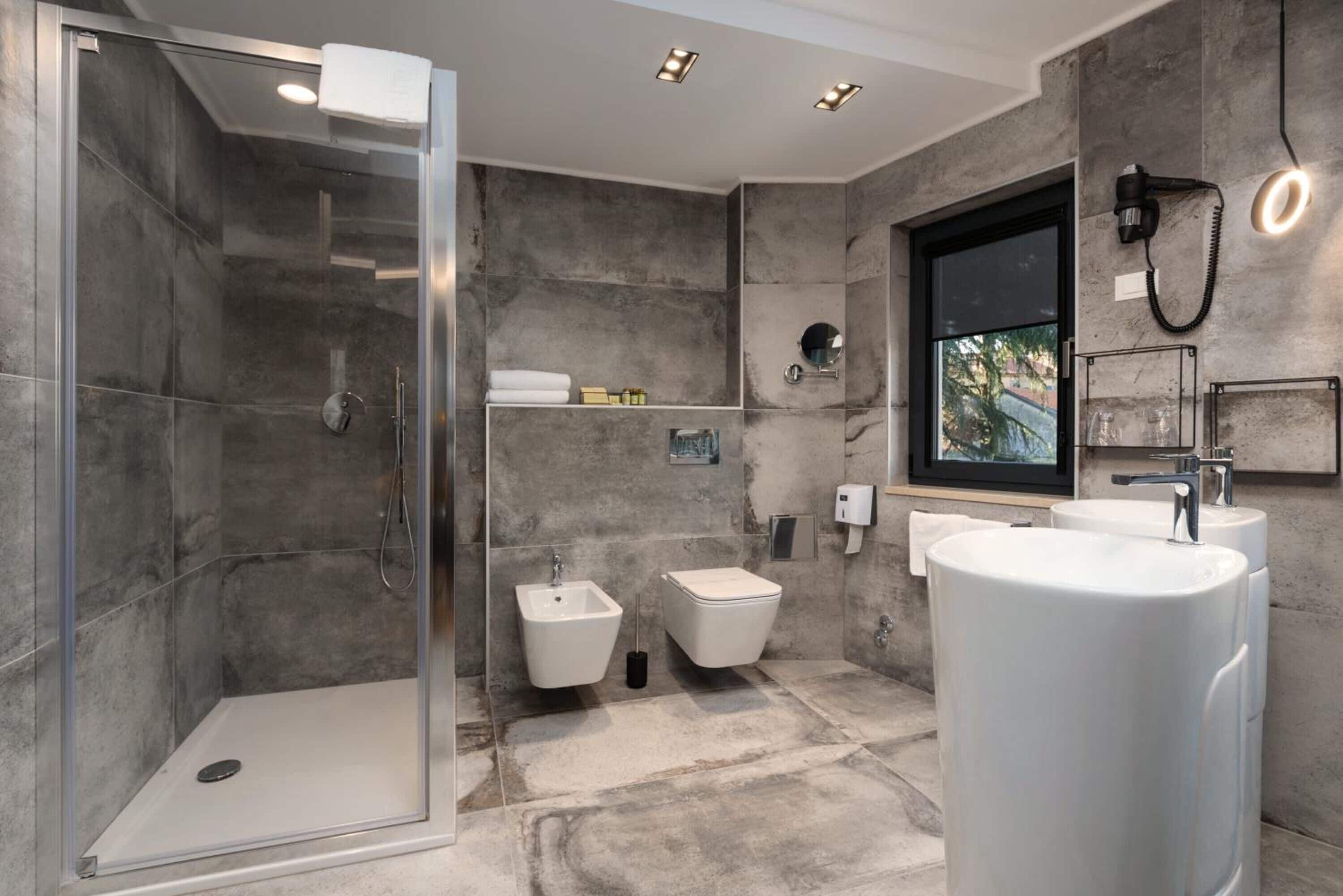 Un baño moderno con ducha de vidrio, un lavamanos grande y un bidé.