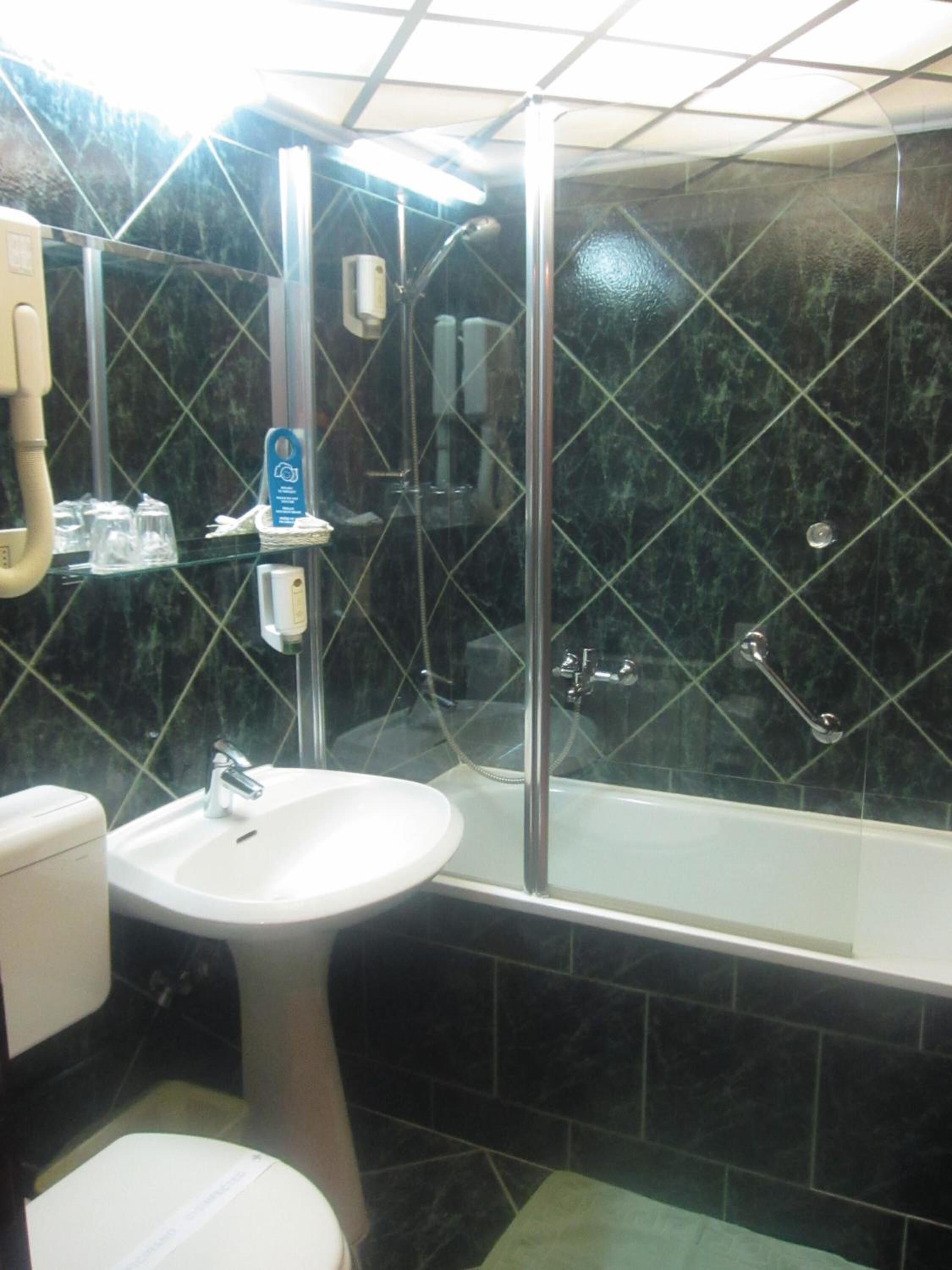 A bathroom with a sink, toilet, and a glass-enclosed shower area.