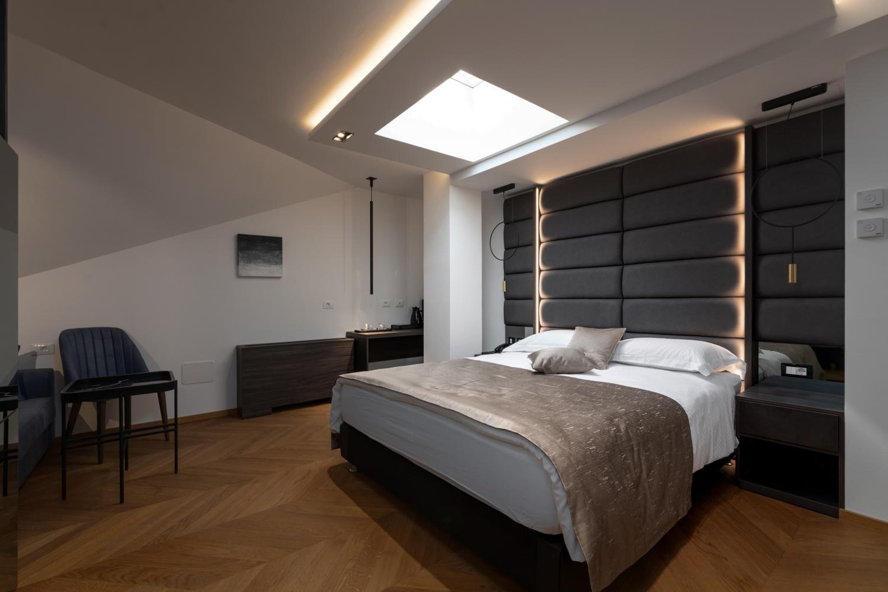 Un dormitorio moderno con una cama grande, un escritorio, una silla y una mesita de noche.