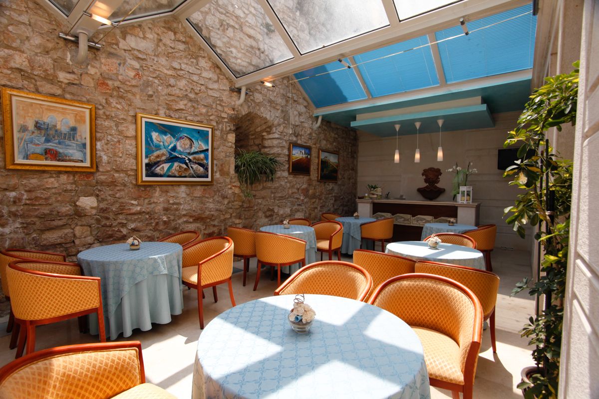 Un restaurante acogedor con paredes de piedra, mesas redondas y sillas anaranjadas.