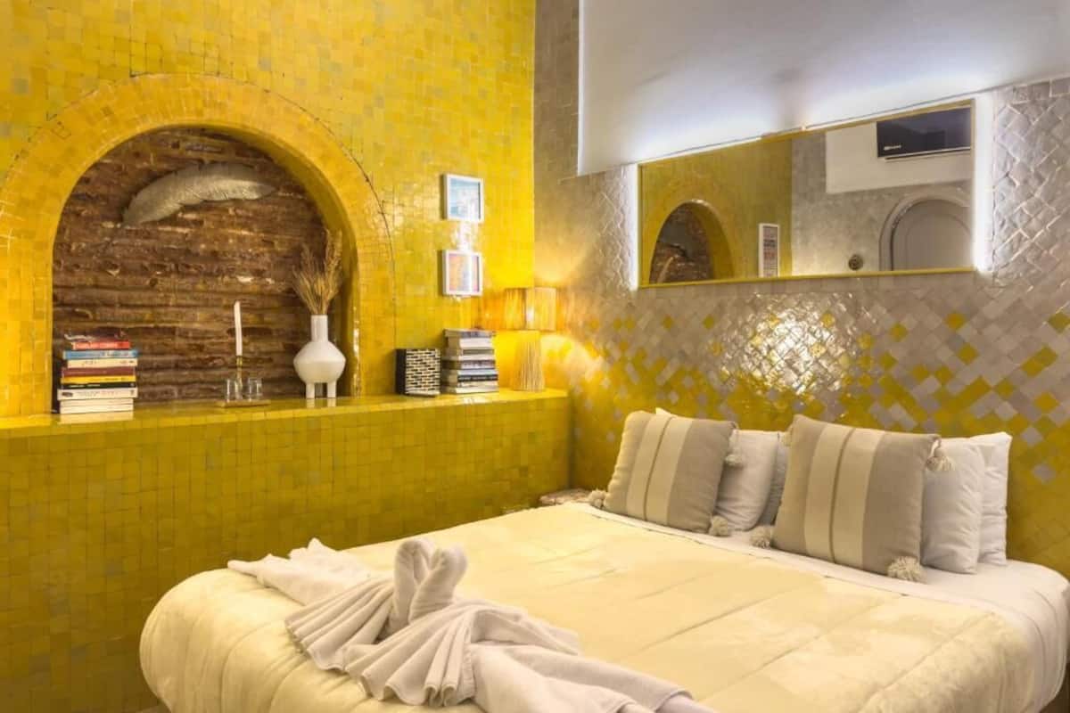 A hotel room with a large bed, a brick wall, and a tiled backsplash.