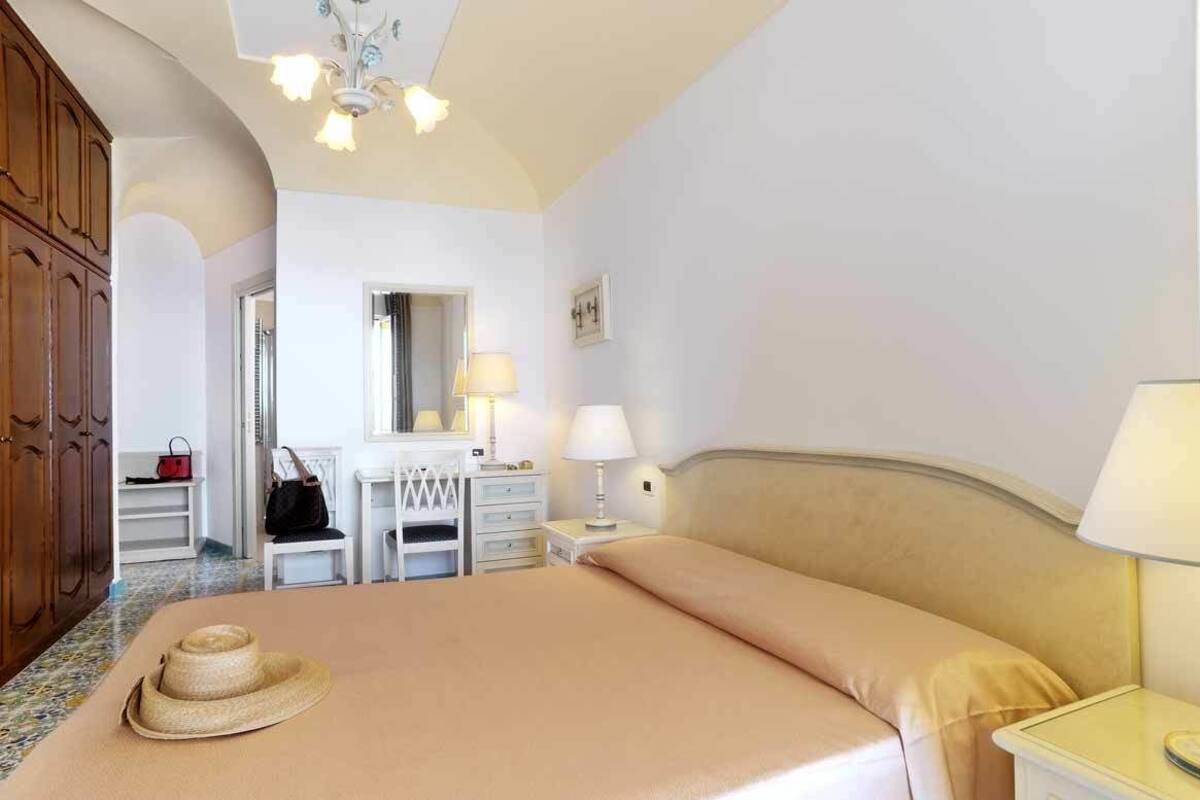 A hotel room with a bed, a nightstand, a dresser, a mirror, and a wardrobe.
