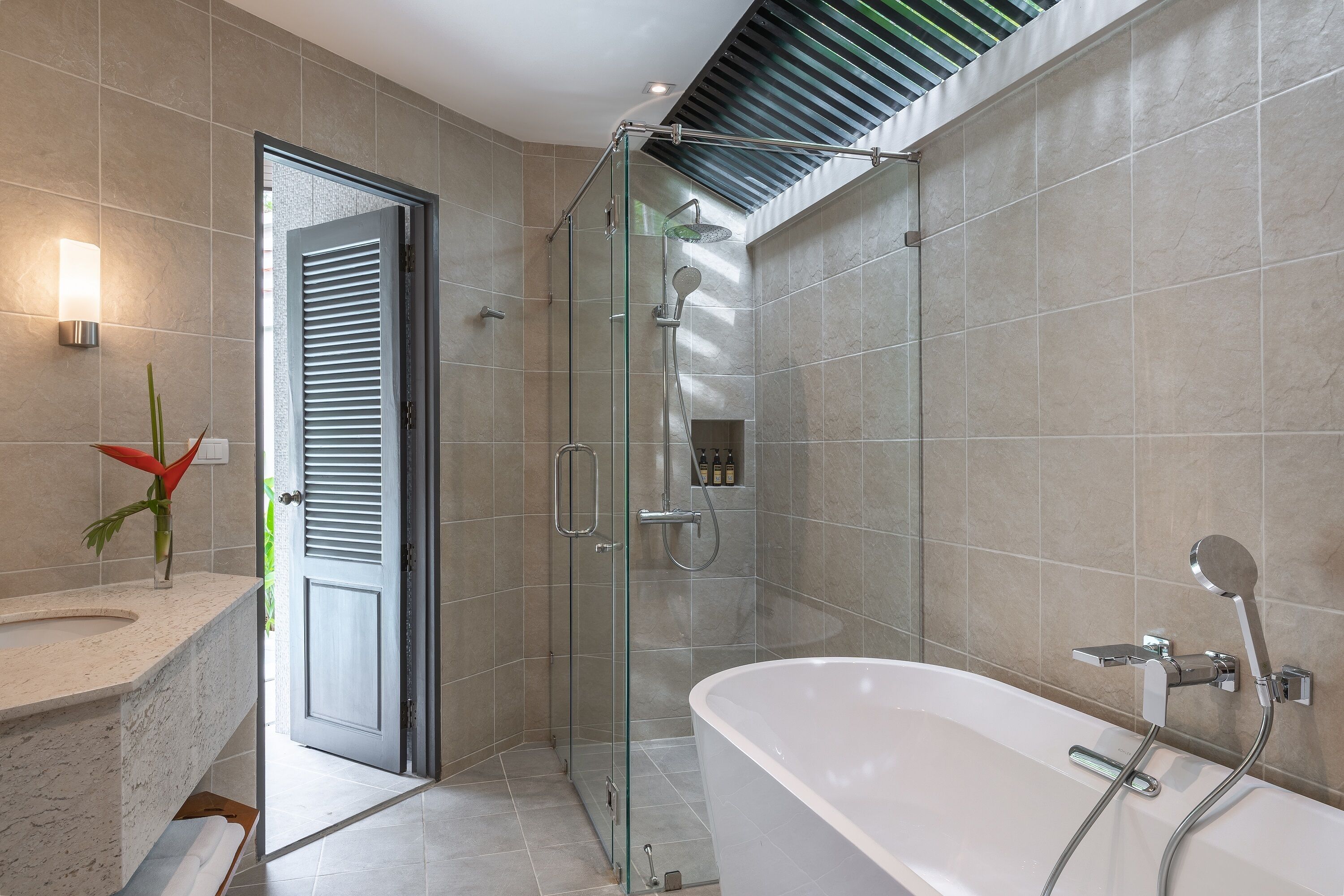 A modern bathroom with a glass-enclosed shower, a freestanding bathtub, and a vanity with a sink and mirror.