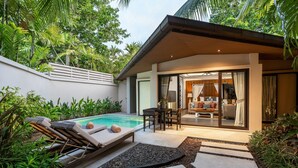 A modern outdoor pool area with lounge chairs, a dining table, and a living area with a sofa and curtains. - Dewa Phuket Resort & Villas (Sa Khu)