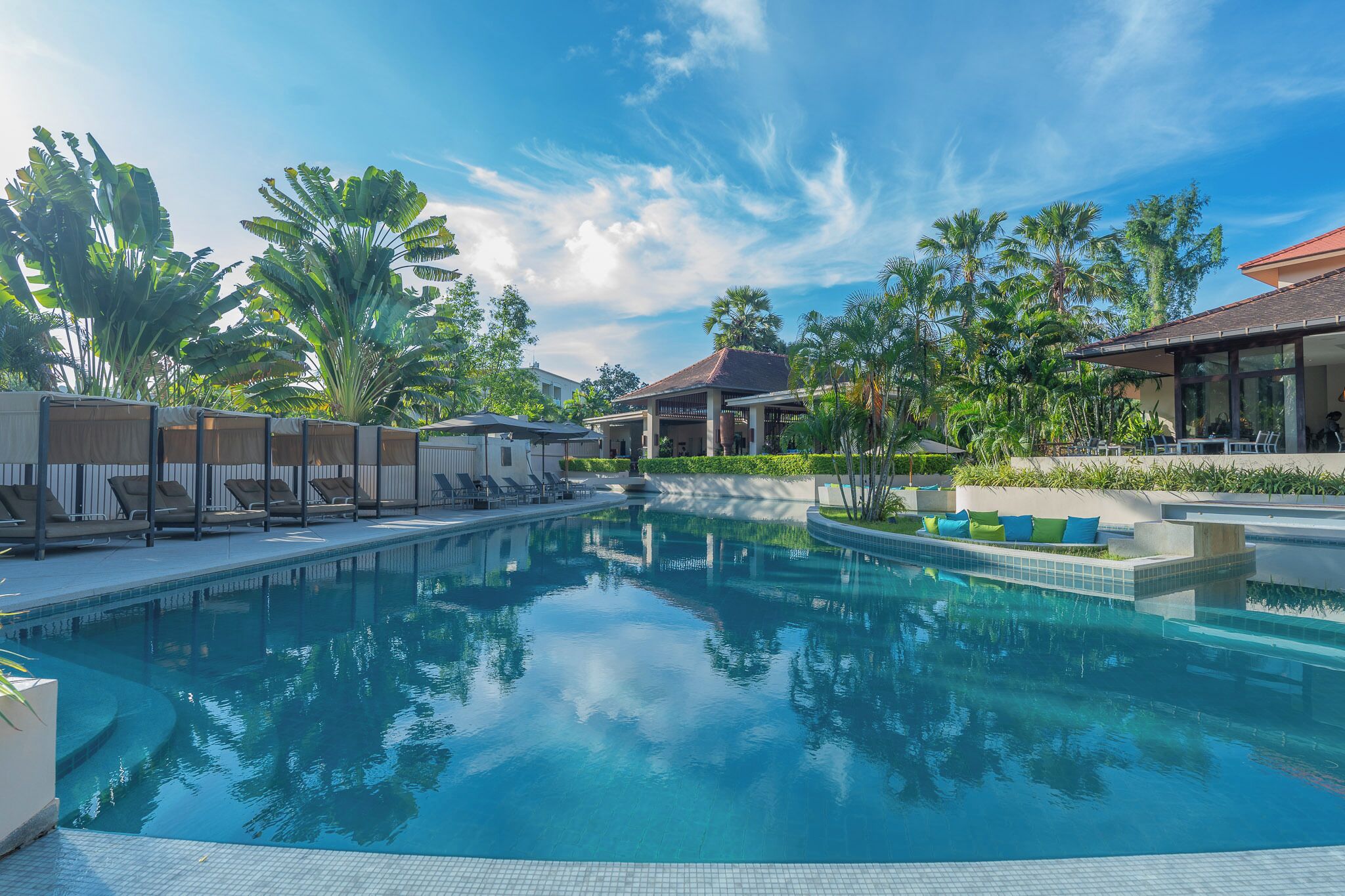 Ein Swimmingpool mit Liegestühlen und Palmen.