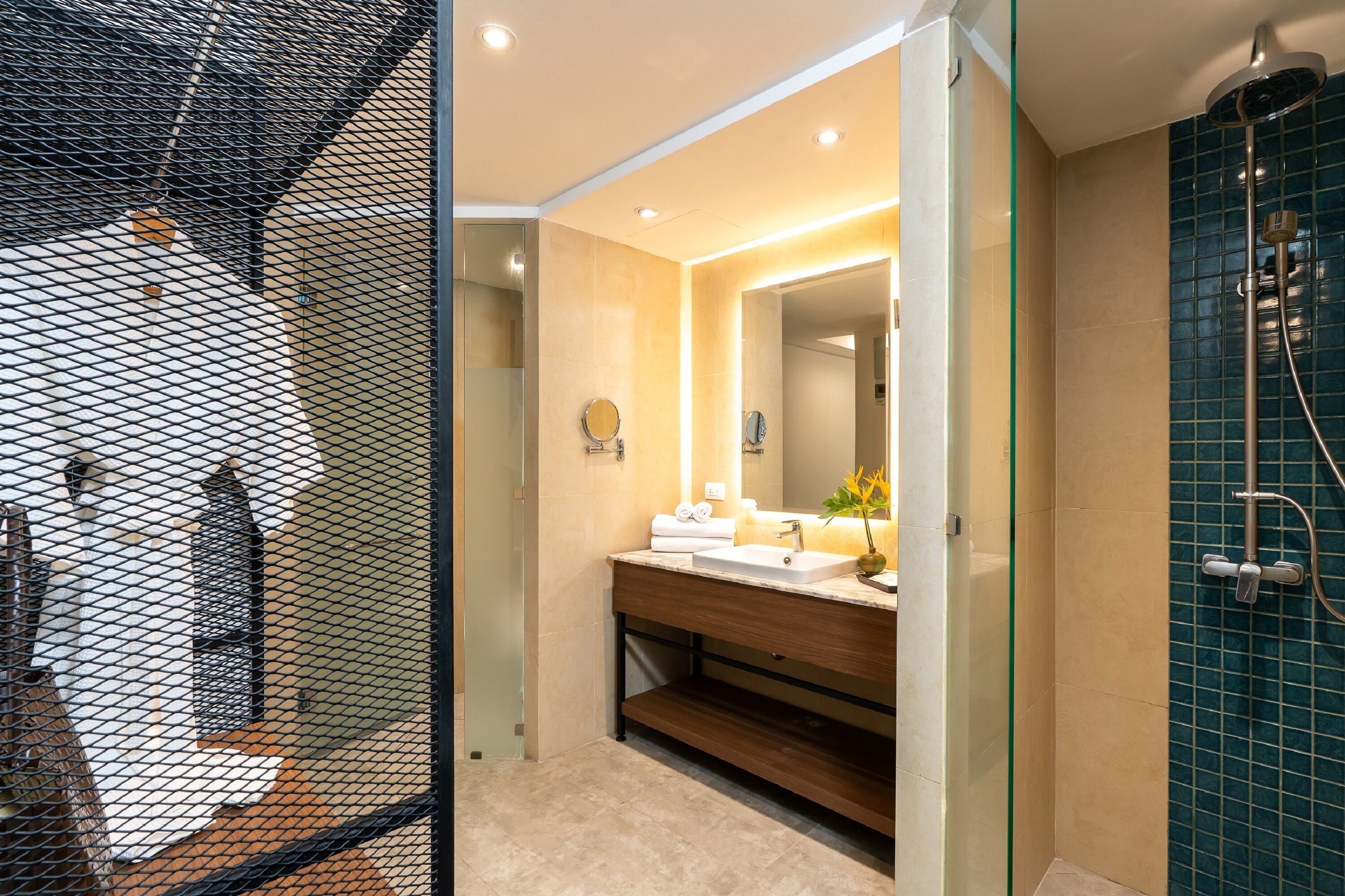 Un baño moderno con mampara de vidrio, lavamanos con espejo y zona de ducha.