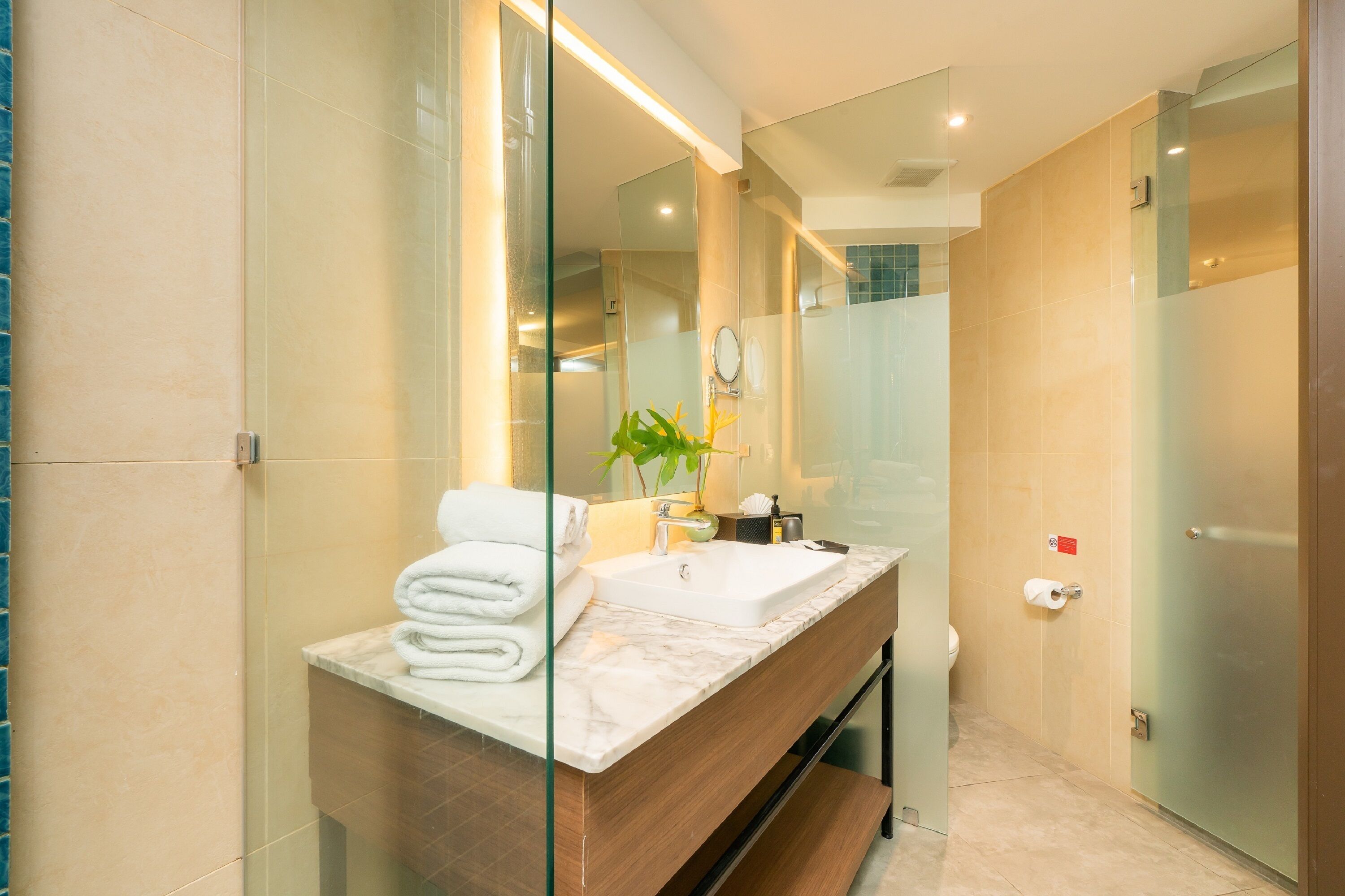 Une salle de bain moderne avec une douche à parois de verre, un lavabo en marbre et un miroir.
