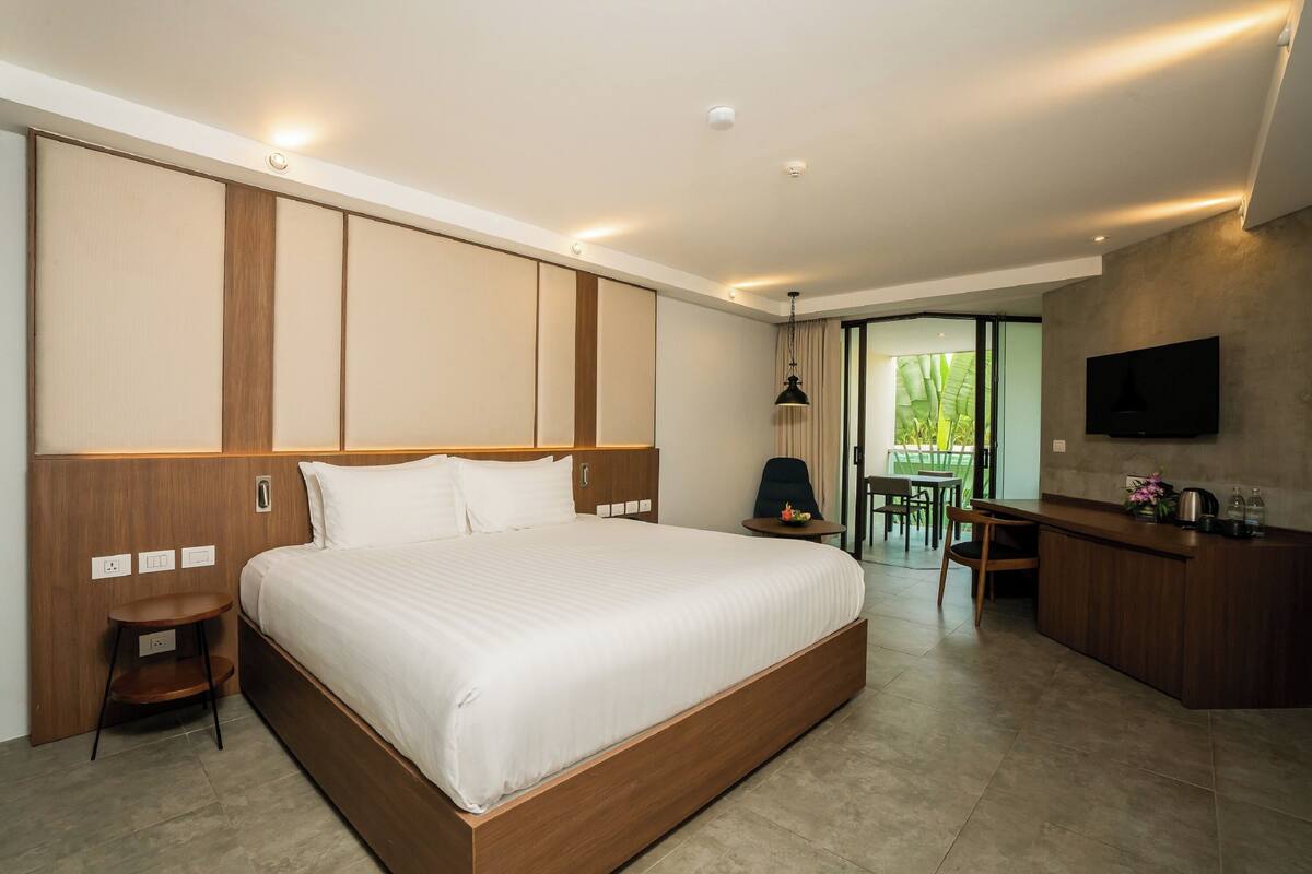 A modern hotel room with a large bed, a desk, and a TV mounted on the wall.