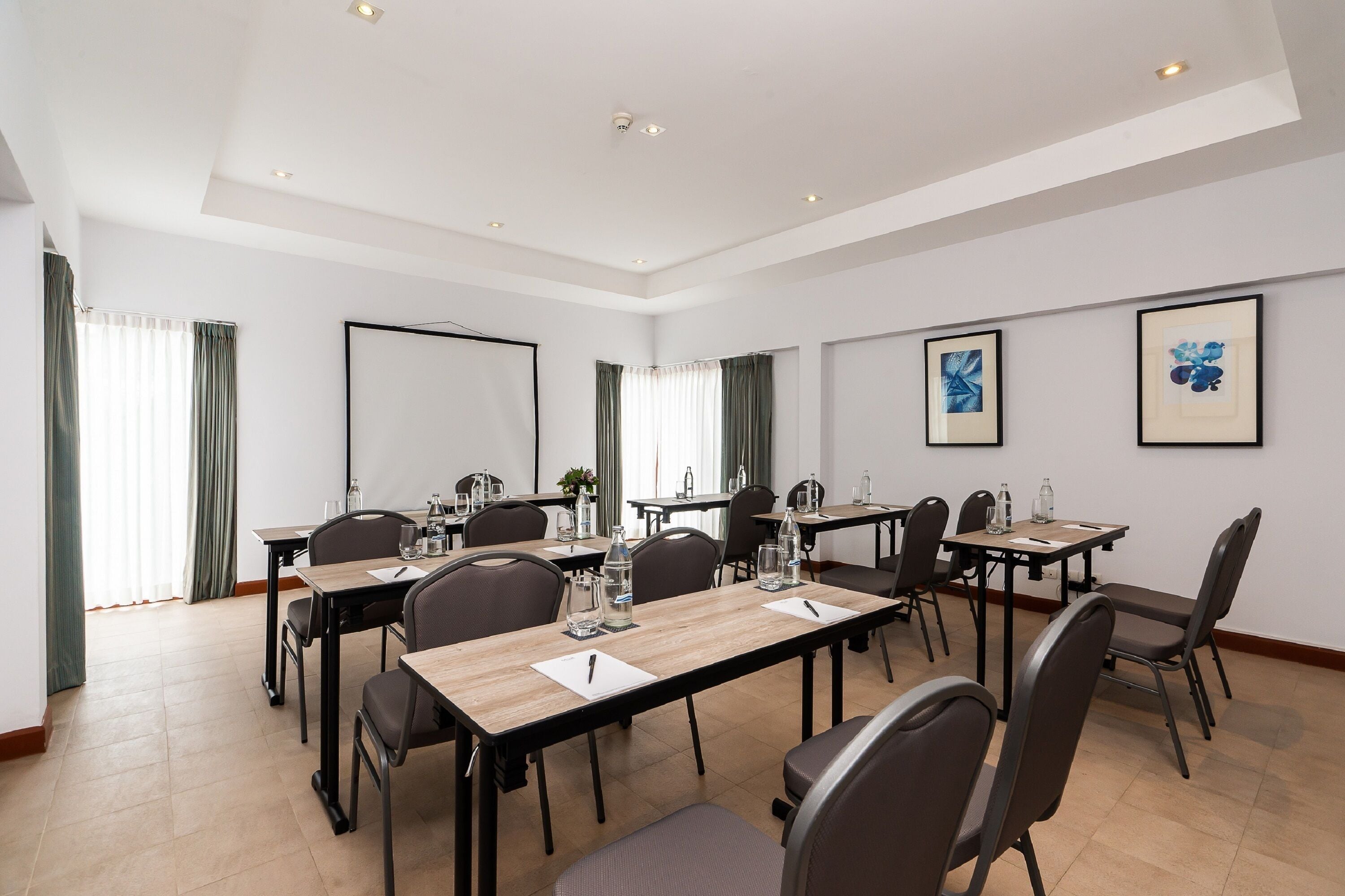 Une salle de conférence équipée de plusieurs tables, de chaises et d’un grand écran.