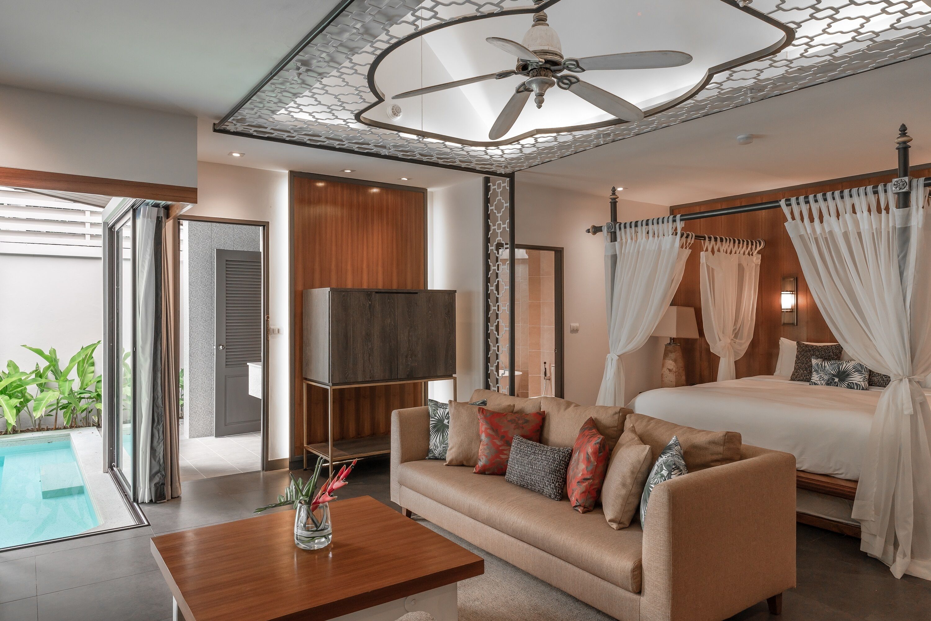 A bedroom with a bed, a sofa, a TV, a ceiling fan, and a pool.