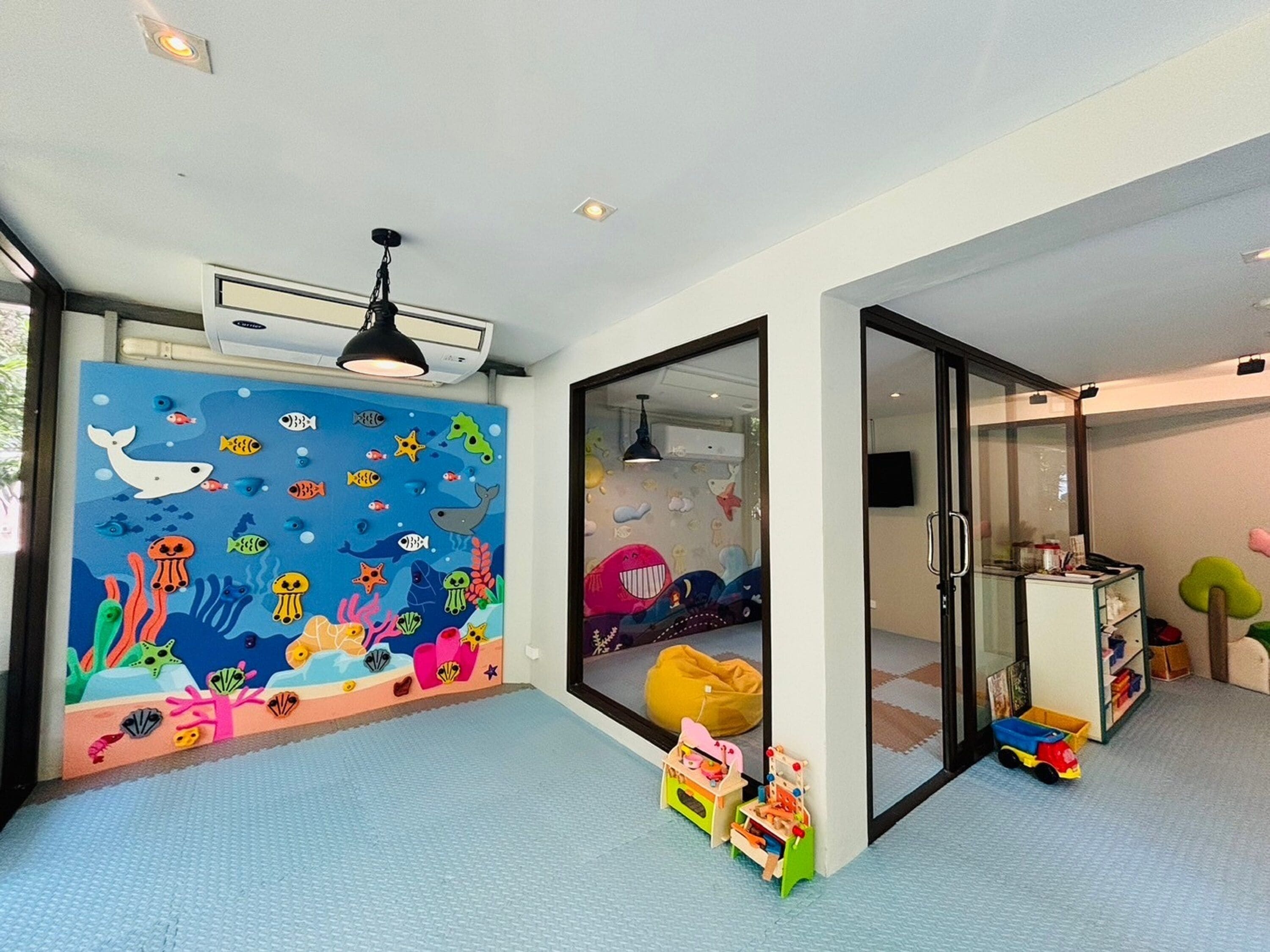 Een kinderspeelkamer met een kleurrijke muurschildering, een zitzak en speelgoed op de vloer.