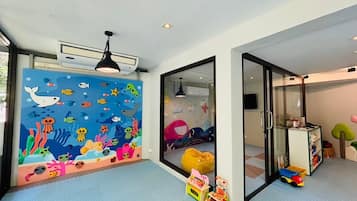 Een kinderspeelkamer met een kleurrijke muurschildering, een zitzak en speelgoed op de vloer.