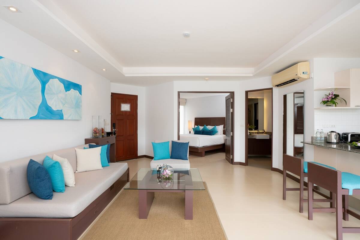 A modern hotel room with a living area, a dining space, and a bedroom.