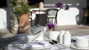 A table set for a meal with white tableware, a teapot, and a potted orchid. - Despotiko Hotel (Volos)