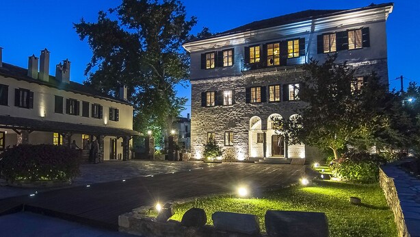 A historic building with a stone facade, multiple windows, and a well-lit entrance. - Despotiko Hotel (Volos)