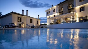 A pool area with lounge chairs and a building with balconies. - Despotiko Hotel (Volos)