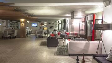 A spacious lobby with a bar area, seating arrangements, and a television screen.
