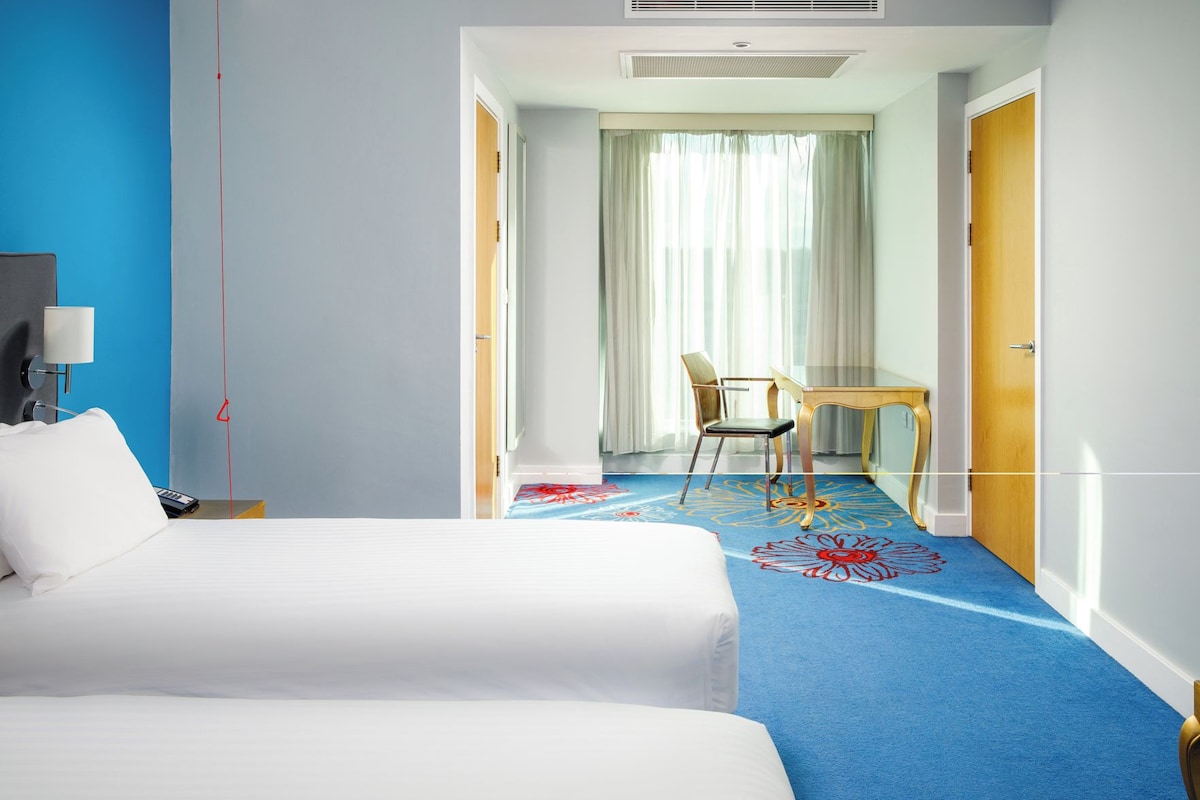 A hotel room with a bed, a desk, and a chair.