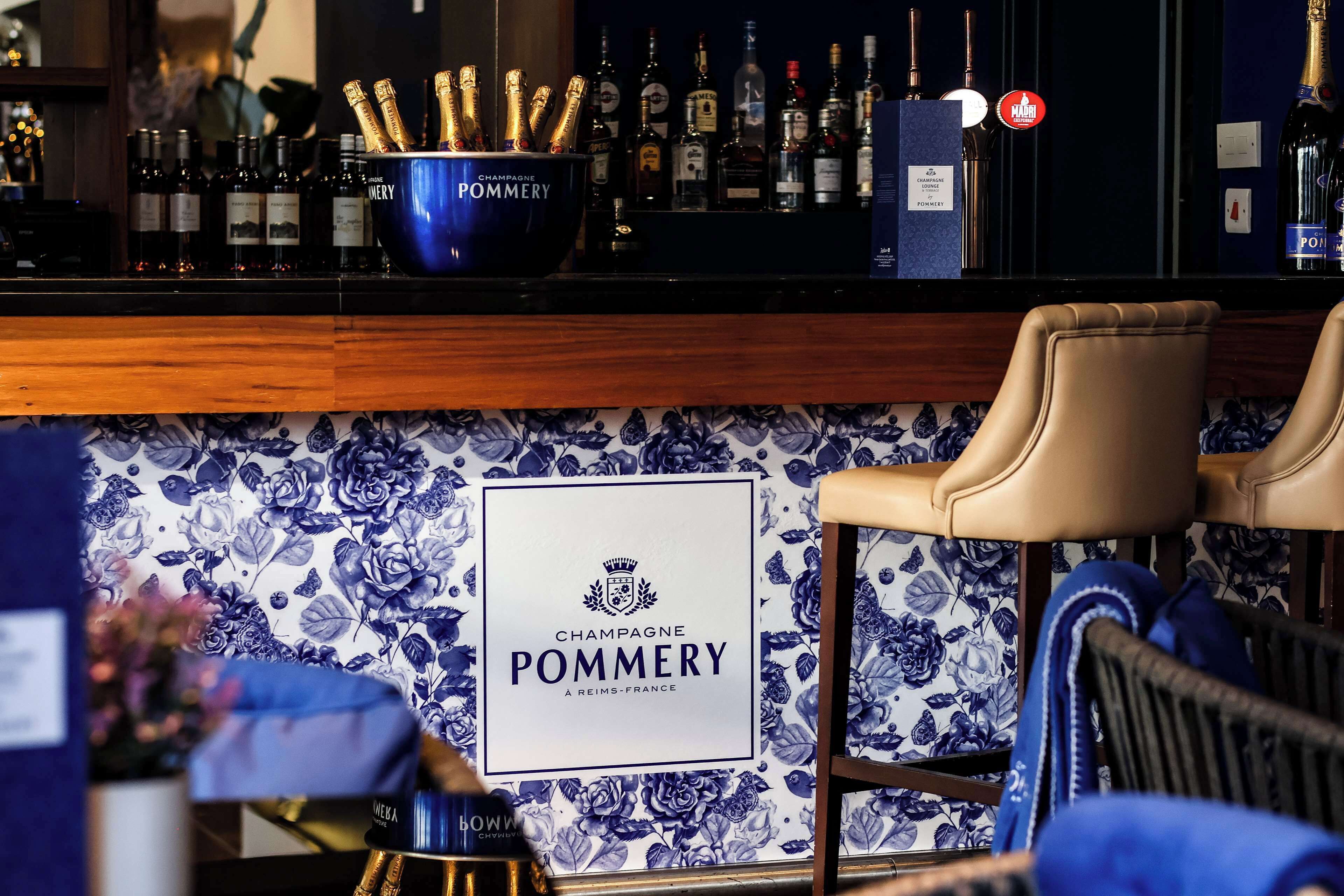 A bar area with a blue bucket labeled 'Champagne Pommery' and a sign stating 'Champagne Pommery A Reims-France'.