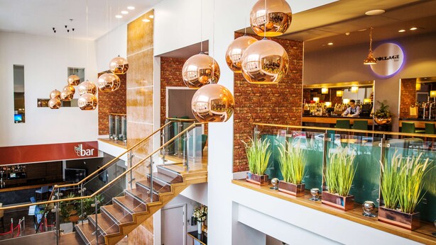 Um interior moderno com área de bar, escada e luminárias esféricas pendentes.