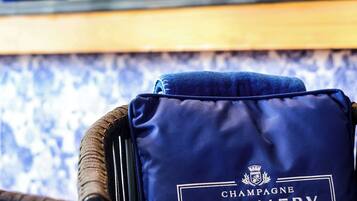 A blue pillow with "Champagne Pommery" branding on a chair.